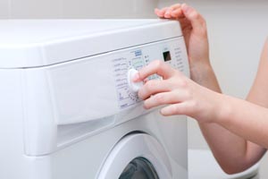 Kobieta nastawia pralkę, naprawa pralek automatycznych